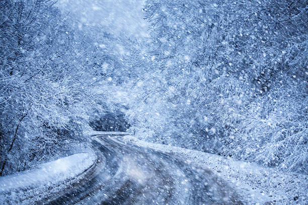 highway in the winter forest at snowfall stock photo