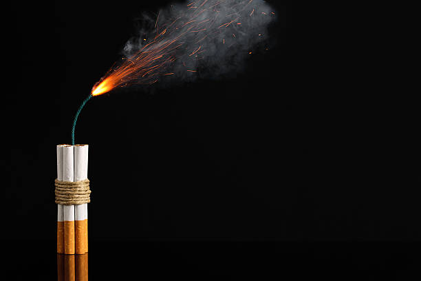 Cigarette Stick Of Dynamite, Smoking Risk Cigarette stick of dynamite about to explode. Concept photo to symbolize the danger of smoking. smoking issues photos stock pictures, royalty-free photos & images