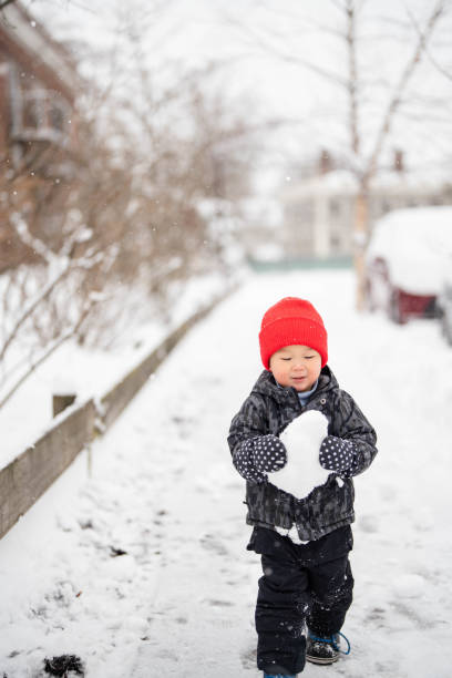 Brothers Sliding in the Snow Outdoors in Winter. They are smiling and having a lot of fun.