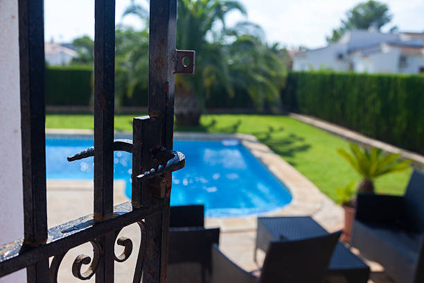 Behind bars Perspective from the terrace of a summer house from the gate playing with the background blur. pool gate stock pictures, royalty-free photos & images
