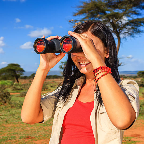 istock Young woman is looking through a binoculars during safari 187113801
