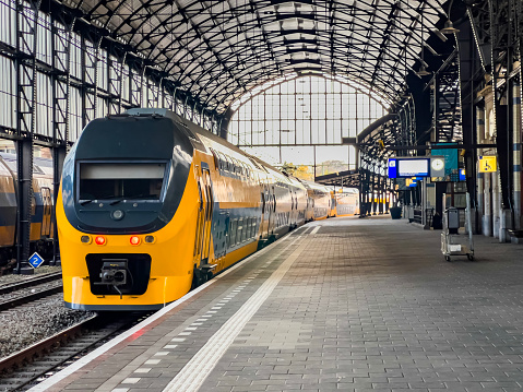 Amsterdam, Netherlands - 12/13/2022: Front view of a yellow two-storey regional train inside the Centraal station.