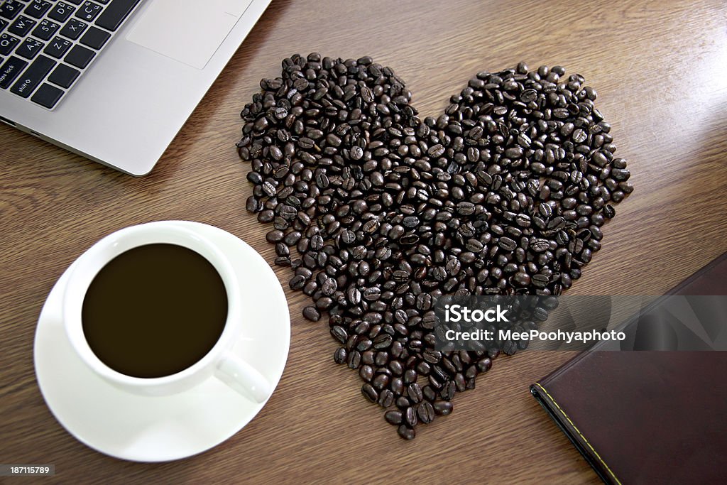 Granos de café dispuestas en forma de corazón cerca de blanco taza. - Foto de stock de Afrodescendiente libre de derechos