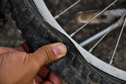 Bike tire was flat and parked on the pavement, the repairman is checking it. Soft and selective focus on tire.