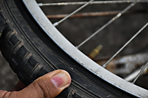 Bike tire was flat and parked on the pavement, the repairman is checking it. Soft and selective focus on tire.