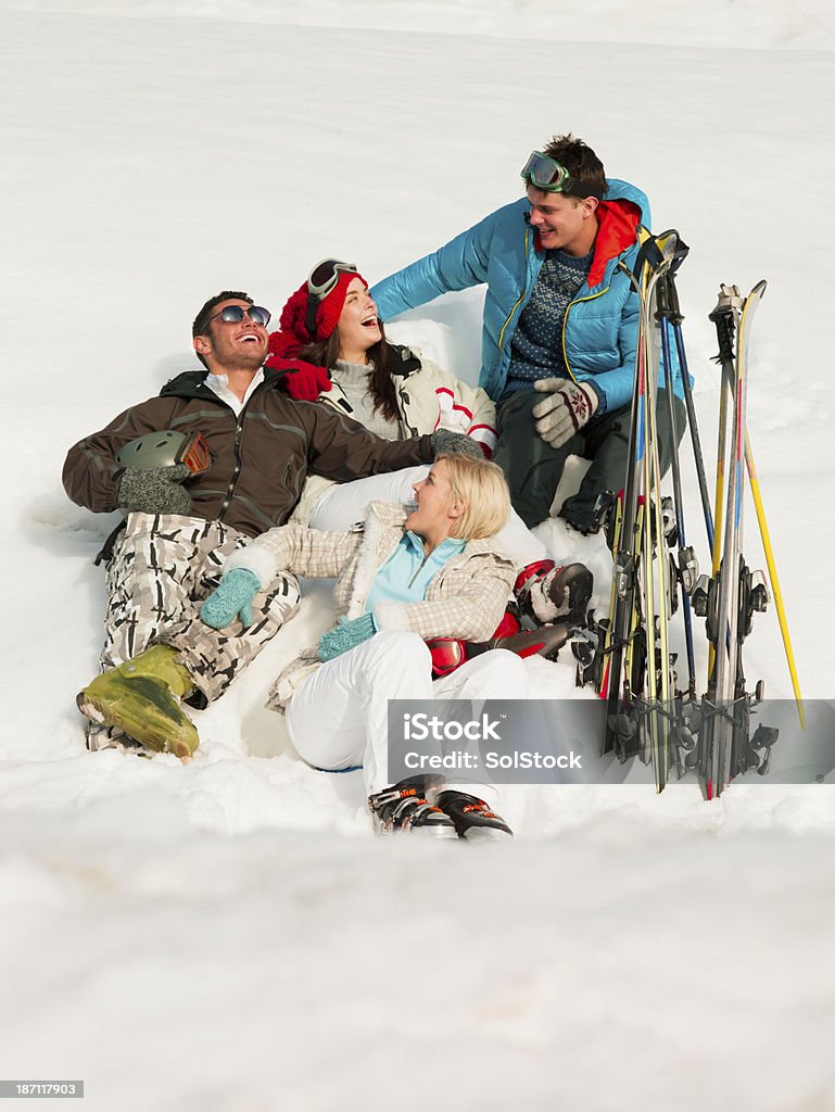 Skiers Sitting In Snow Group of young adults smiling as they sit and lie in the snow with their skis Skiing Stock Photo