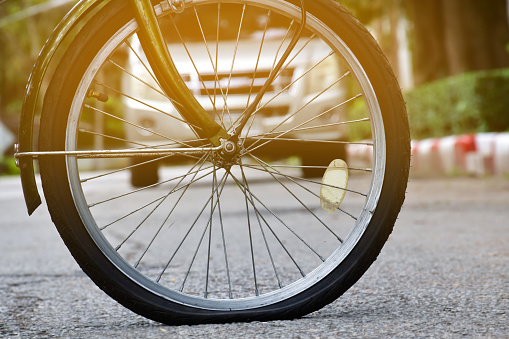Closeup view of flat wheel of bicycle which parked beside the garden, soft and selective focus.