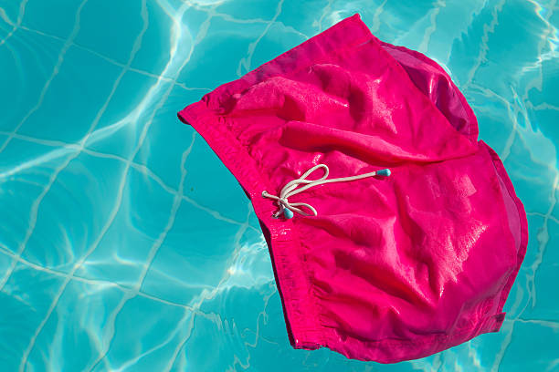 istock Pink swimming shorts floating in the pool 187119124