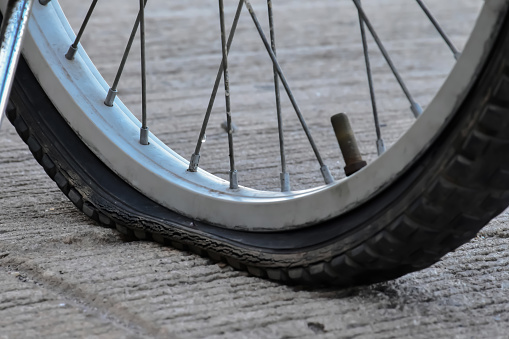 Closeup view of flat wheel of bicycle which parked beside the garden, soft and selective focus.