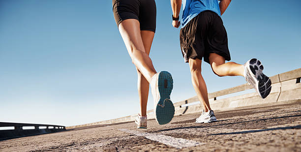 Getting fit for Summer Man and woman running on a street with copyspace running jogging men human leg stock pictures, royalty-free photos & images