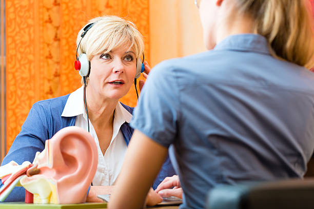 Deaf woman takes a hearing test Older woman or female pensioner with a hearing problem make a hearing test and may need a hearing aid, in the foreground is a model of a human ear ear exam stock pictures, royalty-free photos & images