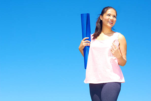 gemischtes frau hält eine flasche wasser und yoga-matte - exercising sensuality water bottle relaxation exercise stock-fotos und bilder