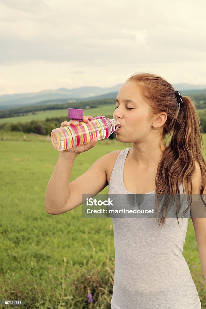 Sanos agua potable chica en la naturaleza después de hacer ejercicios. - Foto de stock de 14-15 años libre de derechos