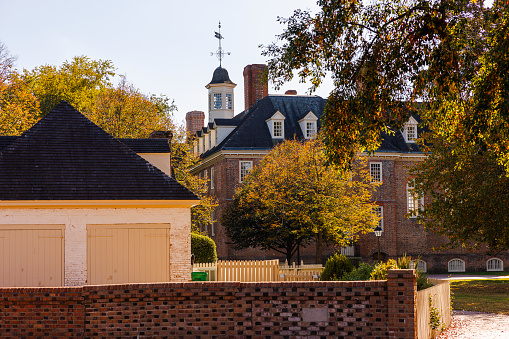 William and Mary college campus with brick houses hidden in autumnal foliage in Colonial Williamsburg, Virginia in sunny day