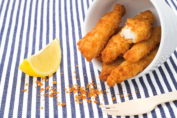 Fish finger sticks Deep fried fish finger sticks and a wedge of lemon fish stick stock pictures, royalty-free photos & images