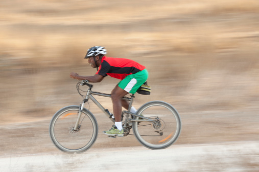 A young man riding a bicycle with high speed, focus on foreground.