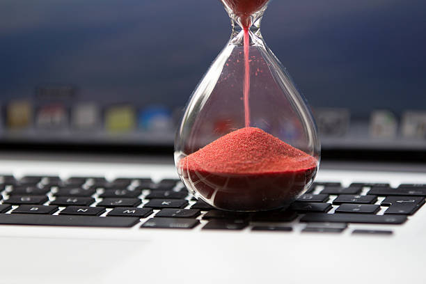 Hourglass on computer keyboard hourglass on keyboard - waiting... slow motion stock pictures, royalty-free photos & images