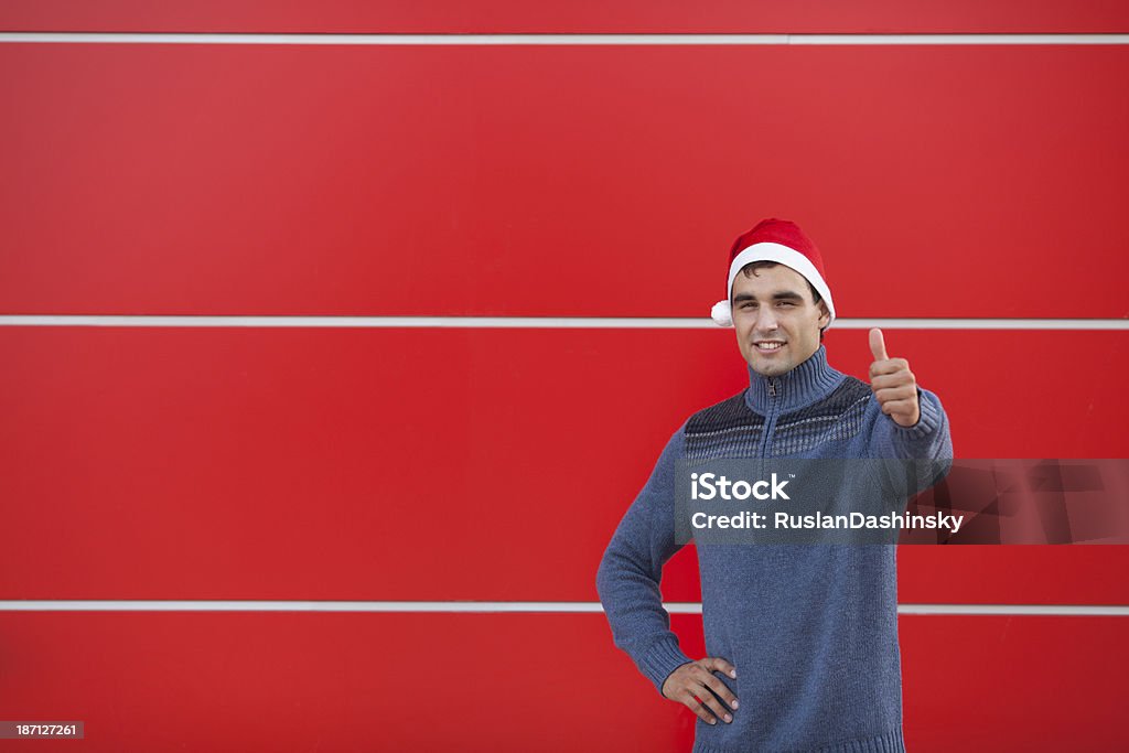 Jeune homme portant Noël bonnet et montrant thumbs up. - Photo de Adulte libre de droits