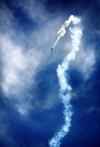 Lightweight plane performing smoke trail tricks