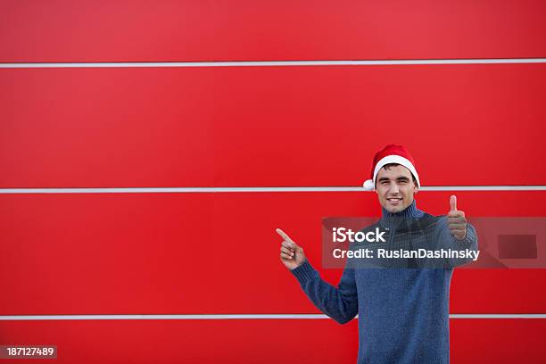 Joven Usando Sombrero Rojo De Navidad De Pie Contra La Pared Foto de stock y más banco de imágenes de Dar masajes