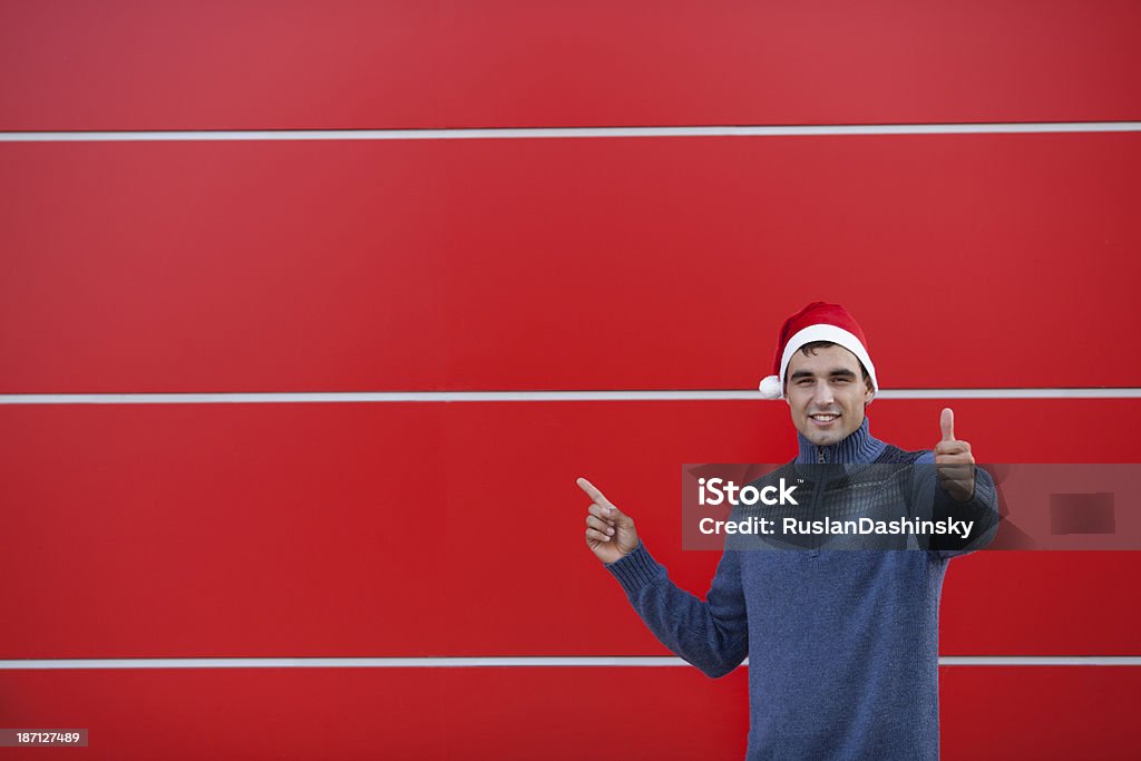 Jovem vestindo Chapéu de Natal vermelho de pé contra a parede. - Royalty-free Massajar Foto de stock