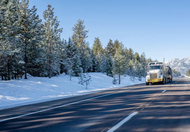 istock White powerful big rig semi truck with oversize load sign on the front transporting oversized cargo on step deck semi trailer running on the winter highway road with snow on the side in Montana 1871283511
