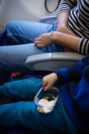 Adorable moments unfold as a cute two and a half year-old boy snacks on a cookie, sitting beside his mom on a plane. Witness the joy and sweetness shared between mother and son during this delightful in-flight experience