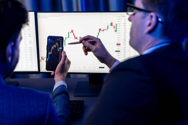 istock Two stock exchange traders researching data on smartphone and laptop. Sellable. 1871287109