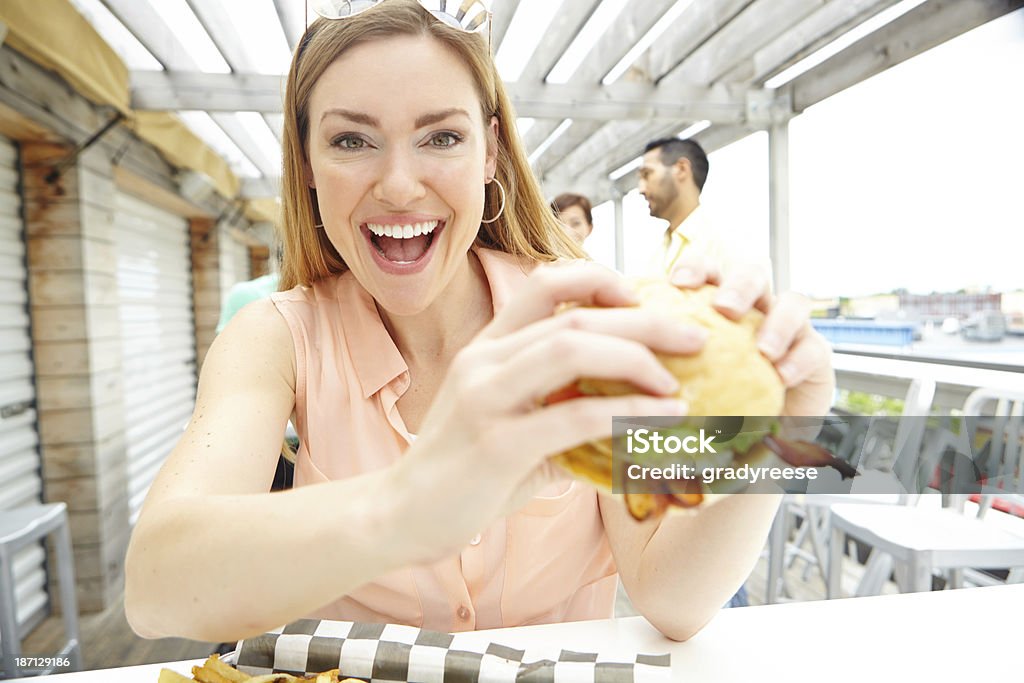 I'm taking this burger down! Portrait of a pretty young woman eating a massive, delicious burger at a restaurant 20-29 Years Stock Photo