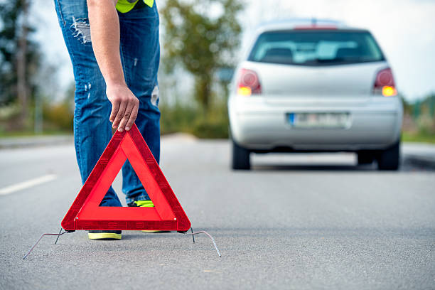 istock A woman putting a warning triangle behind her car 187131302