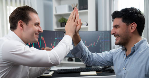 istock Cheerful two smiling stock exchange traders giving high five. Sellable. 1871330774