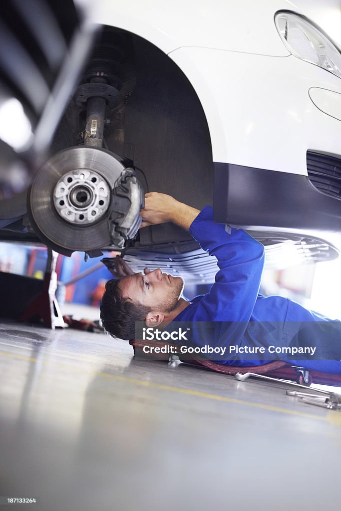 I love to fix cars A car mechanic working on the underside of a car Below Stock Photo