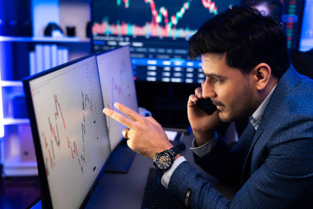 istock Trader calling to broker or partner to analyze data on laptop. Sellable. 1871342189