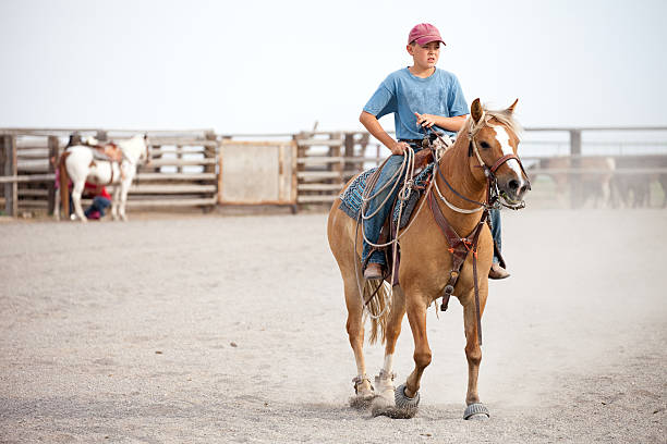 istock Young Boy Riding Horse while Holding Lasso 187138119