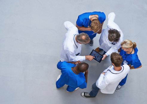 High angle view of a group of doctors standing around a digital tablet