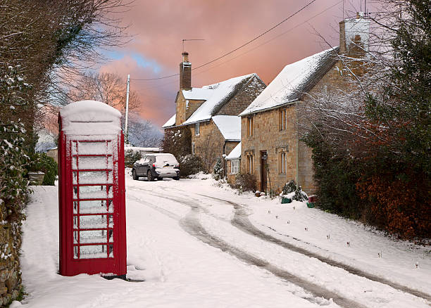 Red phone box and cottages in snow, Cotswolds, Gloucestershire, England.
