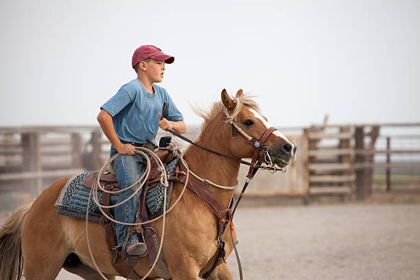 istock Young Boy Riding Horse while Holding Lasso 187142019