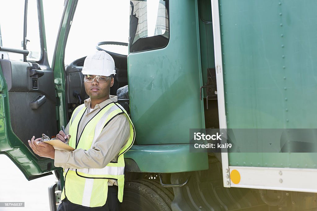 Hombre hispano con camión - Foto de stock de Camión de peso pesado libre de derechos