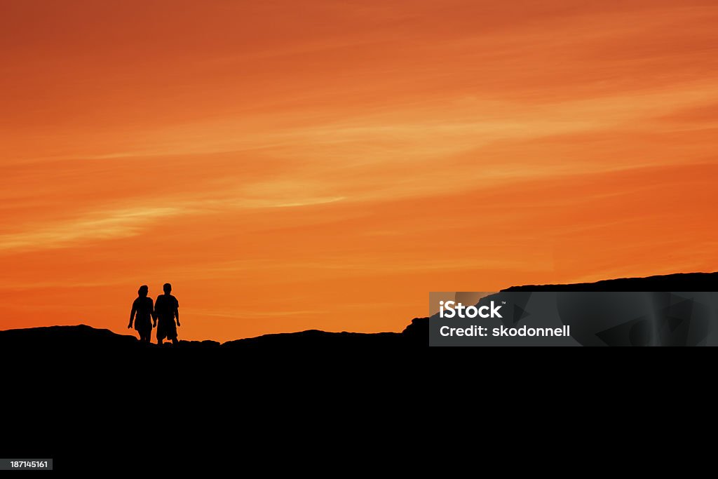 Couple Walking Together at Sunset This is a couple walking on a ridge at sunset. Adult Stock Photo