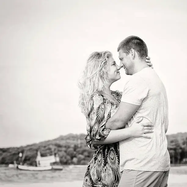 Photo of monotone shot of happy couple in love on the beach