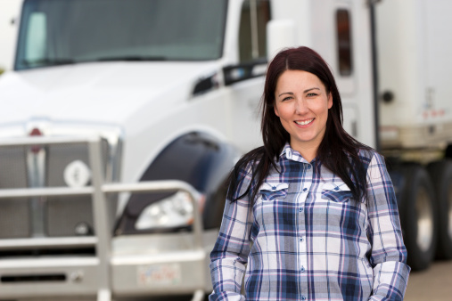 A royalty free image from the trucking industry of a female truck driver in front of her semi truck.