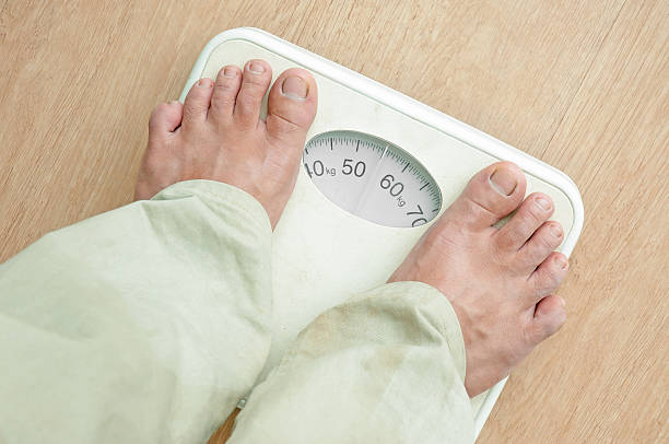 istock Man standing on weight scales with bare foot 187146500
