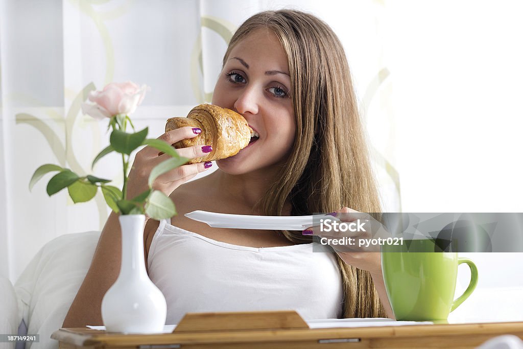Woman having breakfast in bed woman eating croissants in bed Adult Stock Photo
