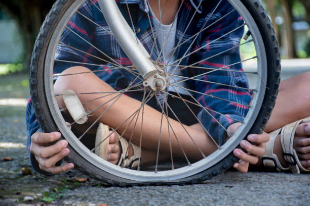 Closeup front wheel of bicycle which is flat and broken of asian boy behind, soft and selective focusใ