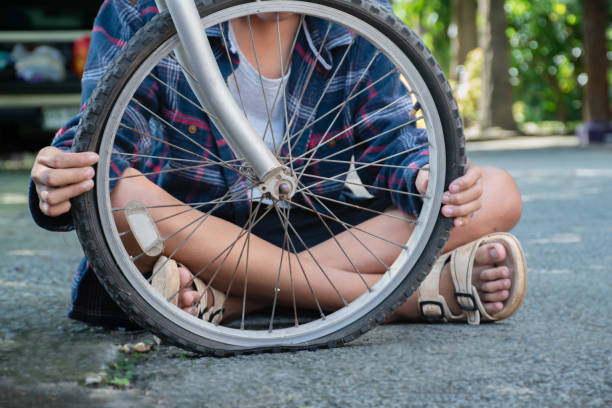 Closeup front wheel of bicycle which is flat and broken of asian boy behind, soft and selective focusใ