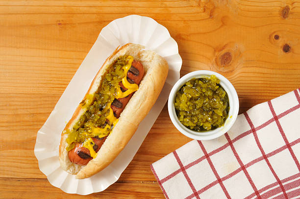 Hot dog with relish A hot dog with mustard and relish on a rustic wooden table relish stock pictures, royalty-free photos & images