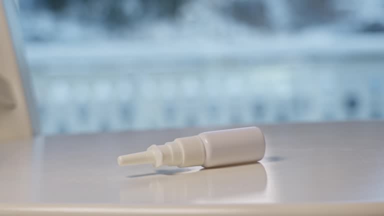 Nasal spray bottle pushed and falling onto white surface table, slow motion