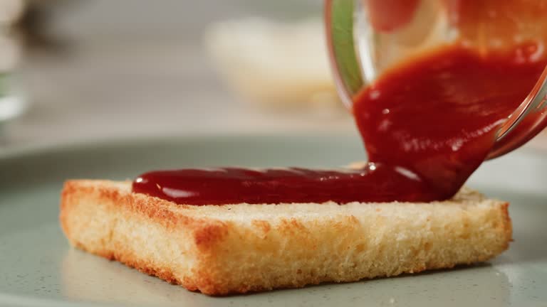 Adding red sauce jam on fried bread close-up. Cooking sandwich at cafe. Pouring tomato sauce on top. Food concept