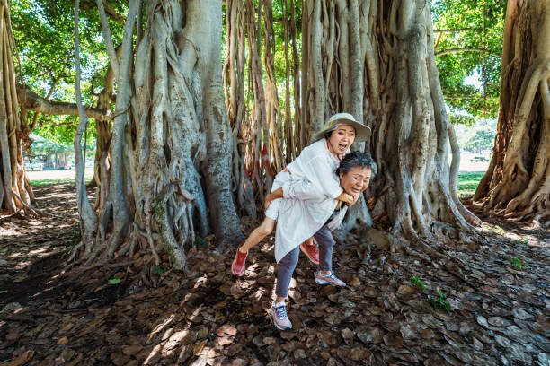 Senior woman giving her friend a piggy back ride while on a hike