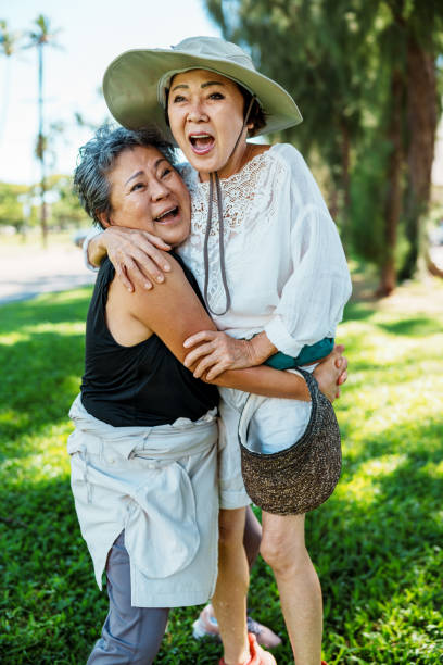 Two senior Korean women laugh and affectionately embrace